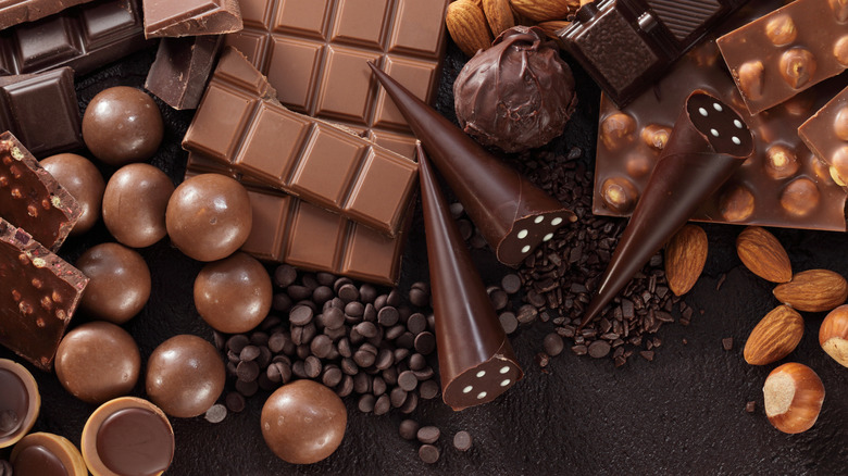 Many types of chocolate - chocolate bars (dark, milk, and with nuts), different types of chocolate candies, and 3 chocolate cones. There are also 2 kinds of chocolate chips and some nuts.